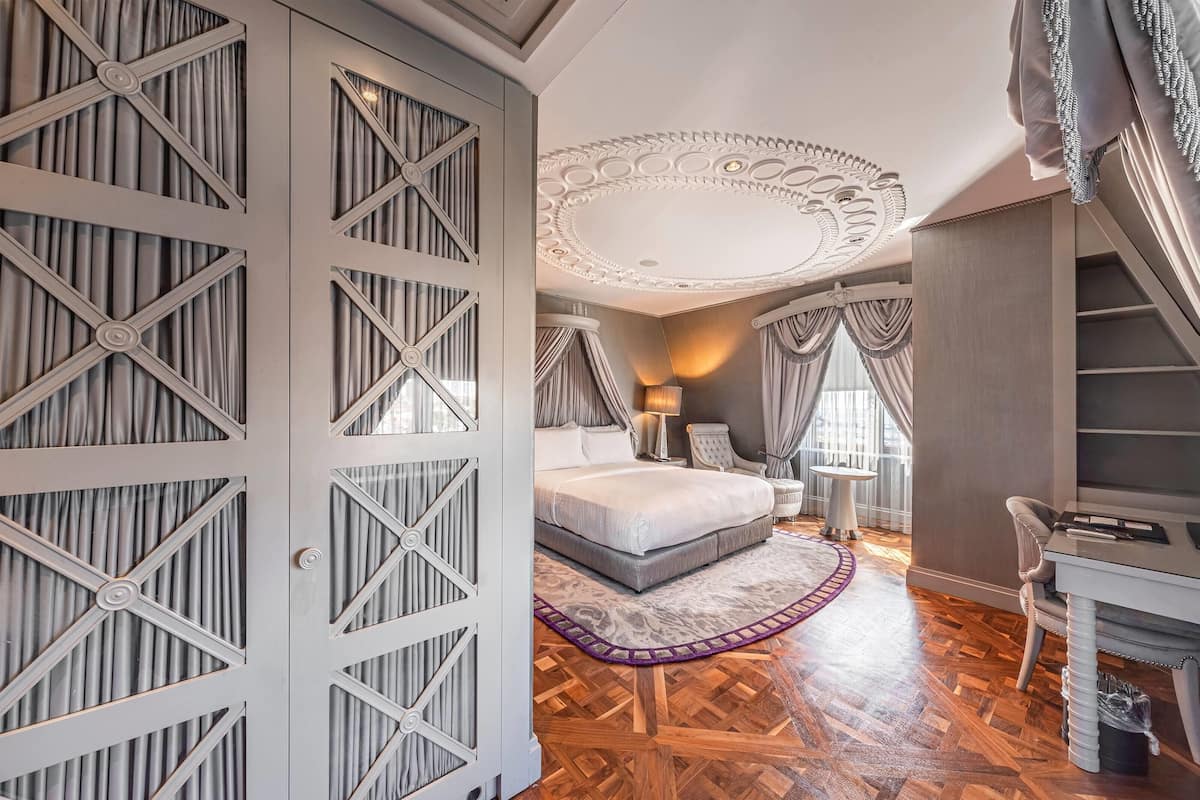 A bedroom with a large bed, a desk, and a chair.