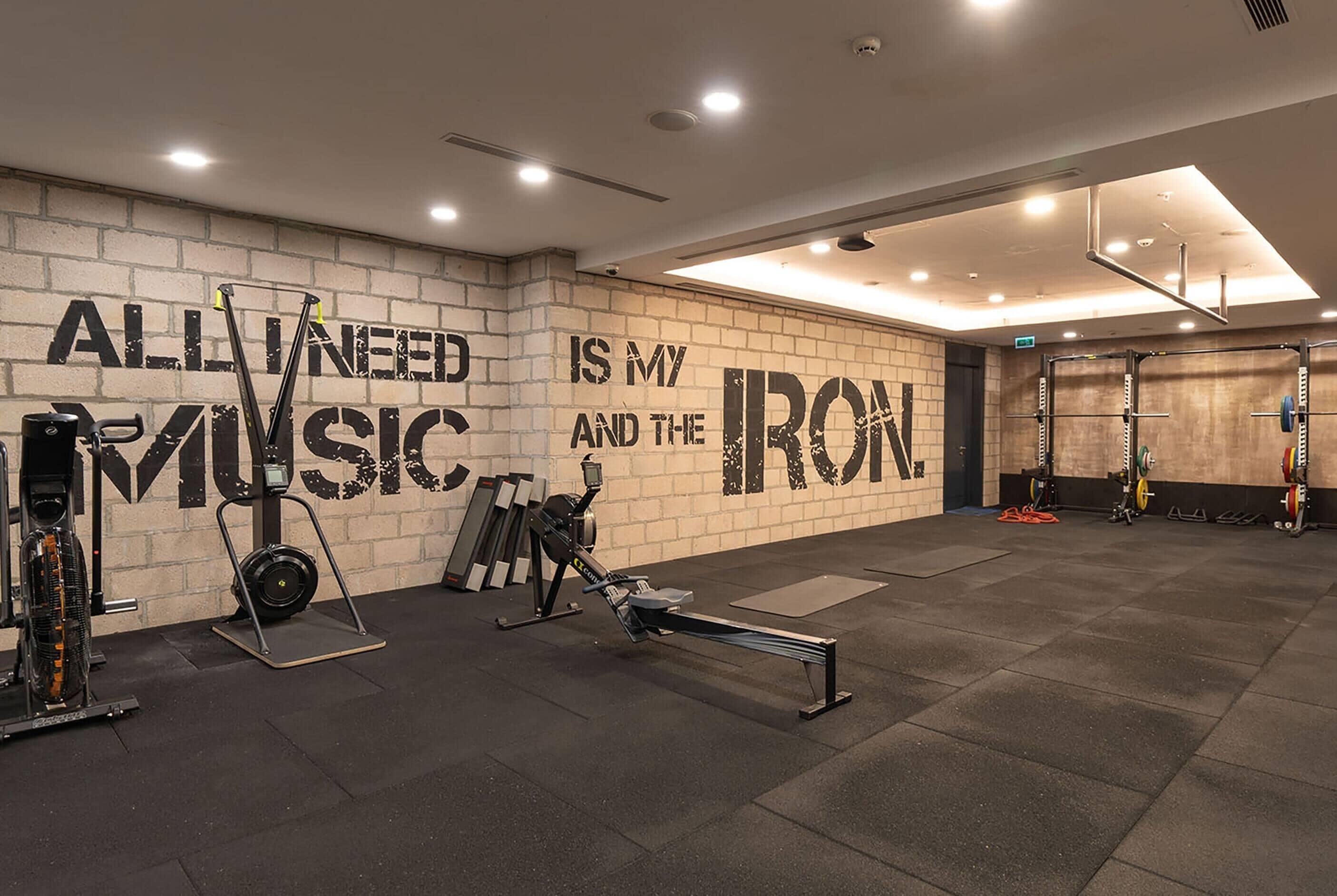 A gym with exercise equipment and a motivational quote on the wall.