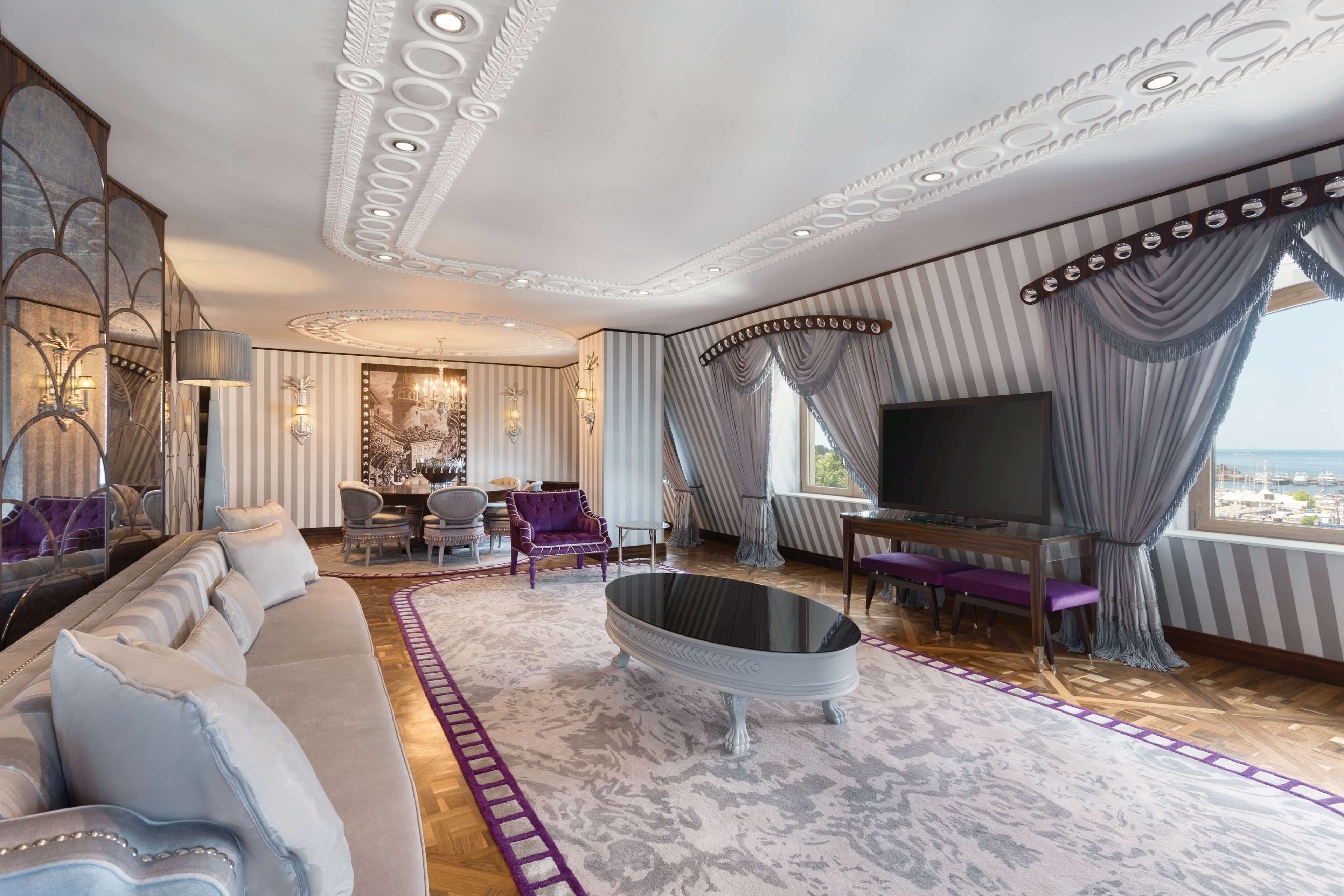 Een luxueuze woonkamer met een grote bank, een salontafel met glazen blad en een televisie.