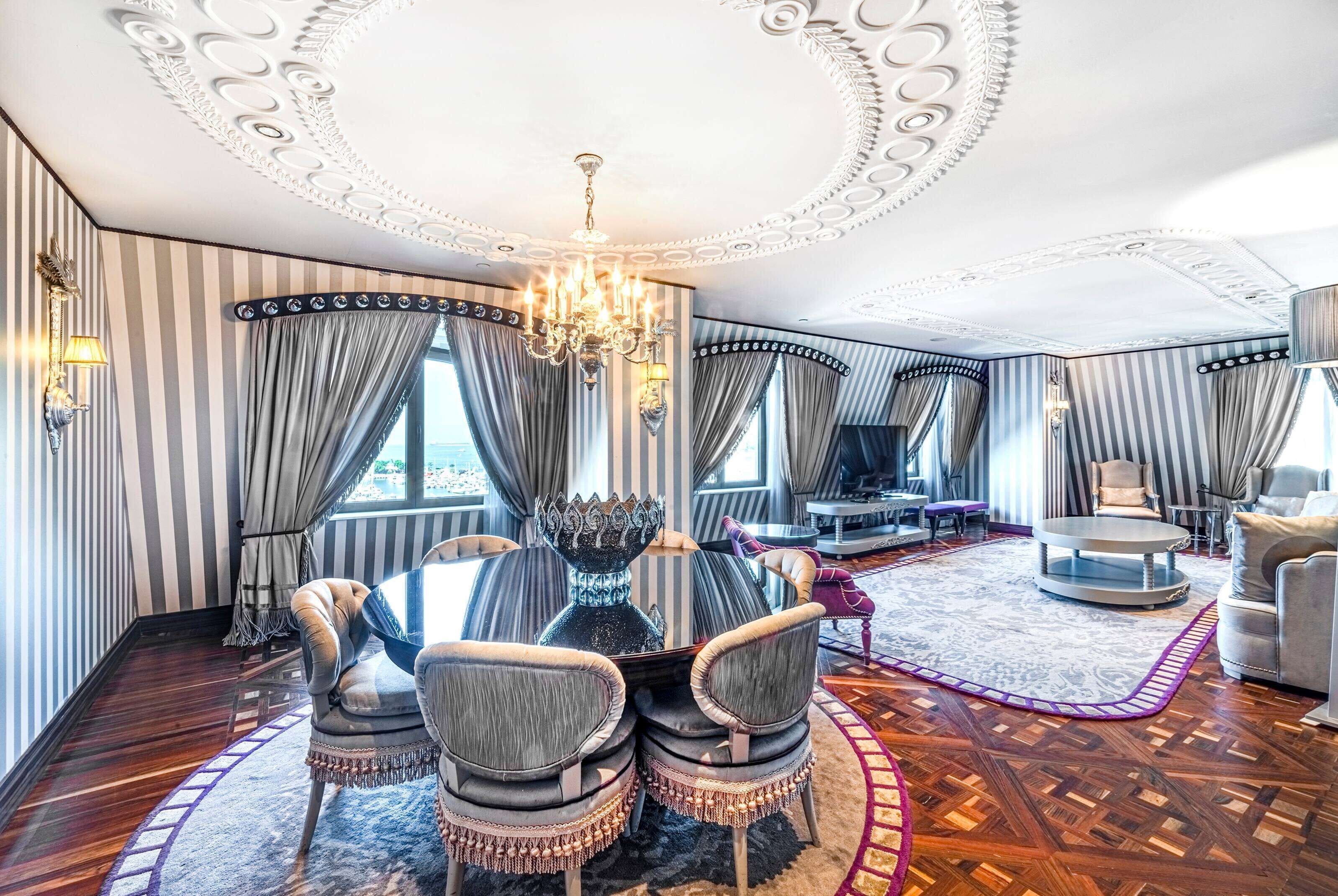 Ein luxuriöses Zimmer mit einem runden Esstisch, gestreifter Gardine und einem Chandelier.