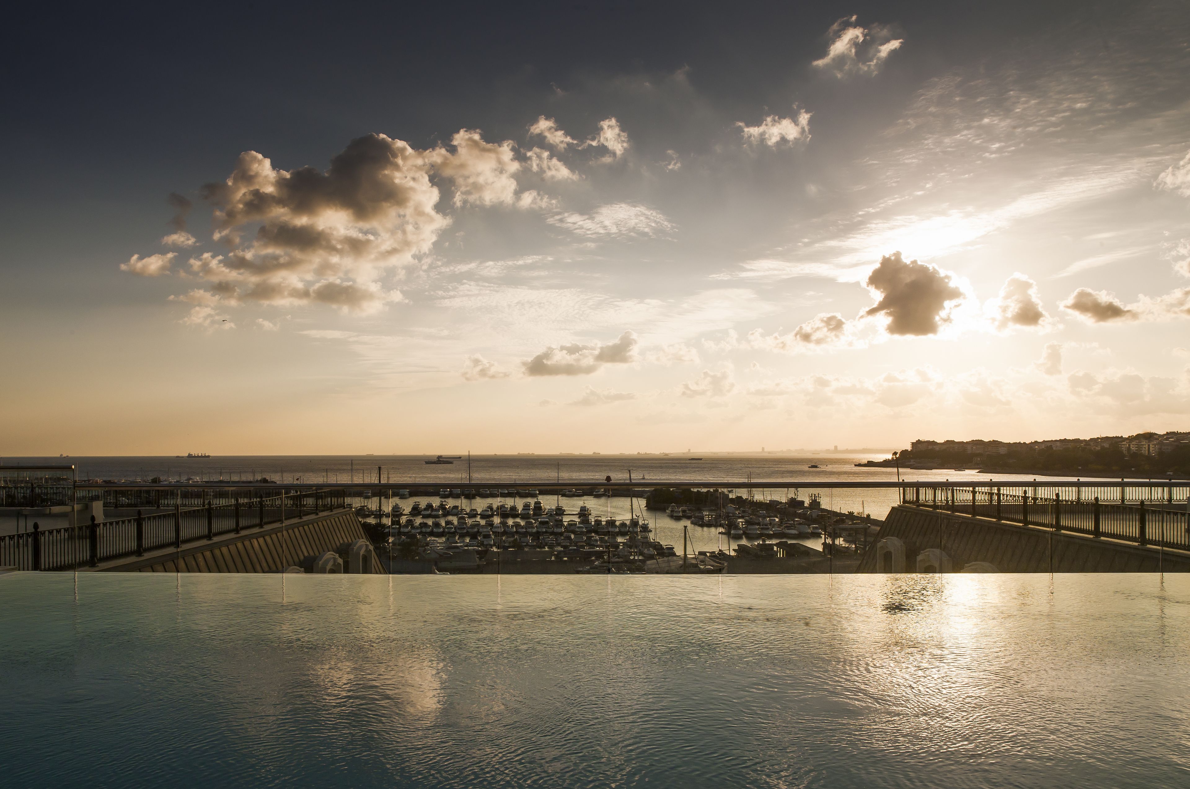 A marina with boats docked, a bridge, and a sunset over the water.
