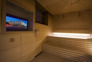 Una sauna con panche in legno e uno schermo televisivo che mostra una vista cittadina.