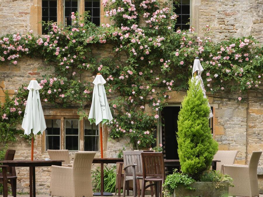 Ein Steinhaus mit Garten-Terrasse, ausgestattet mit Korbmöbeln und Sonnenschirmen.