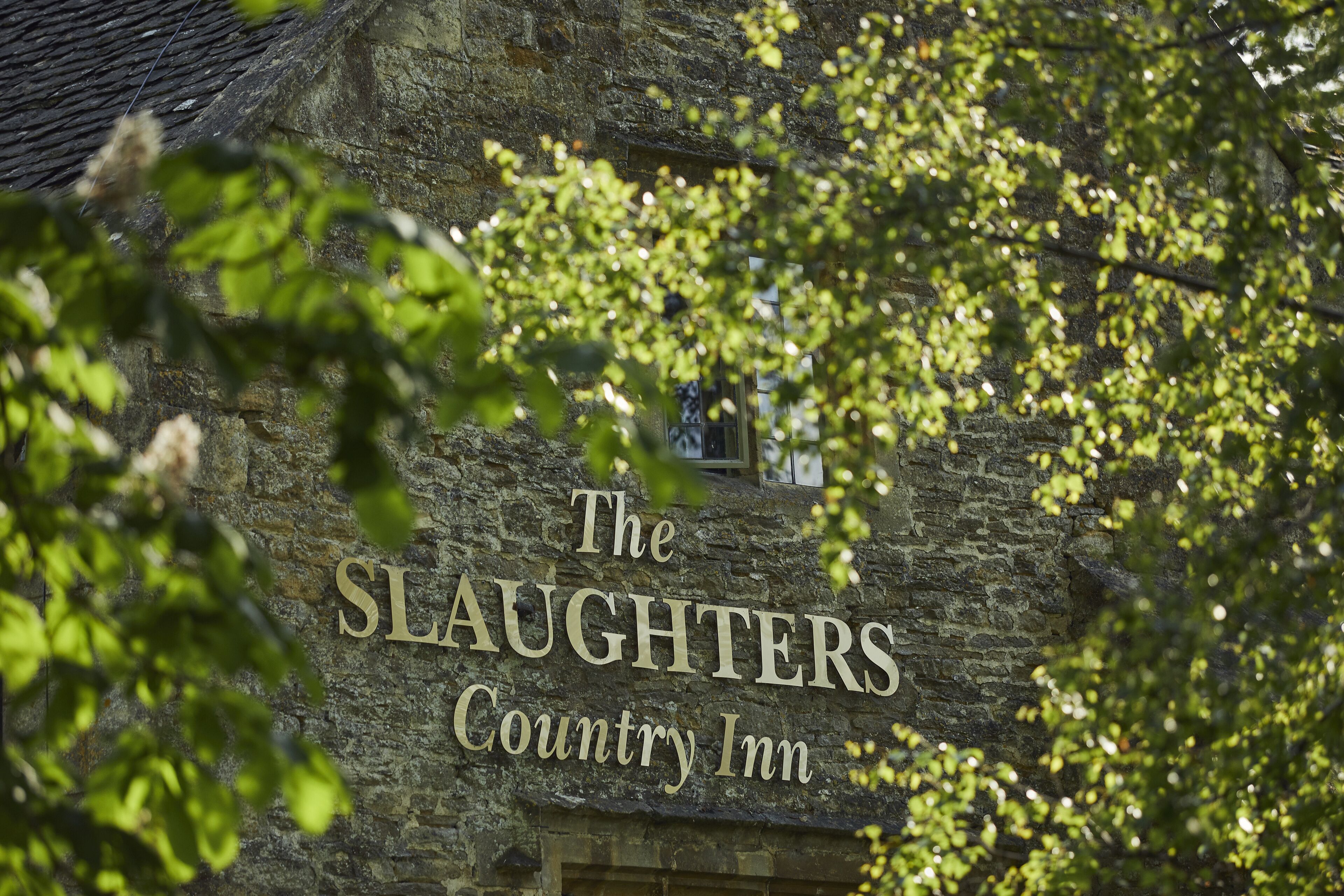 Un edificio de piedra con un letrero que dice "The Slaughters Country Inn".