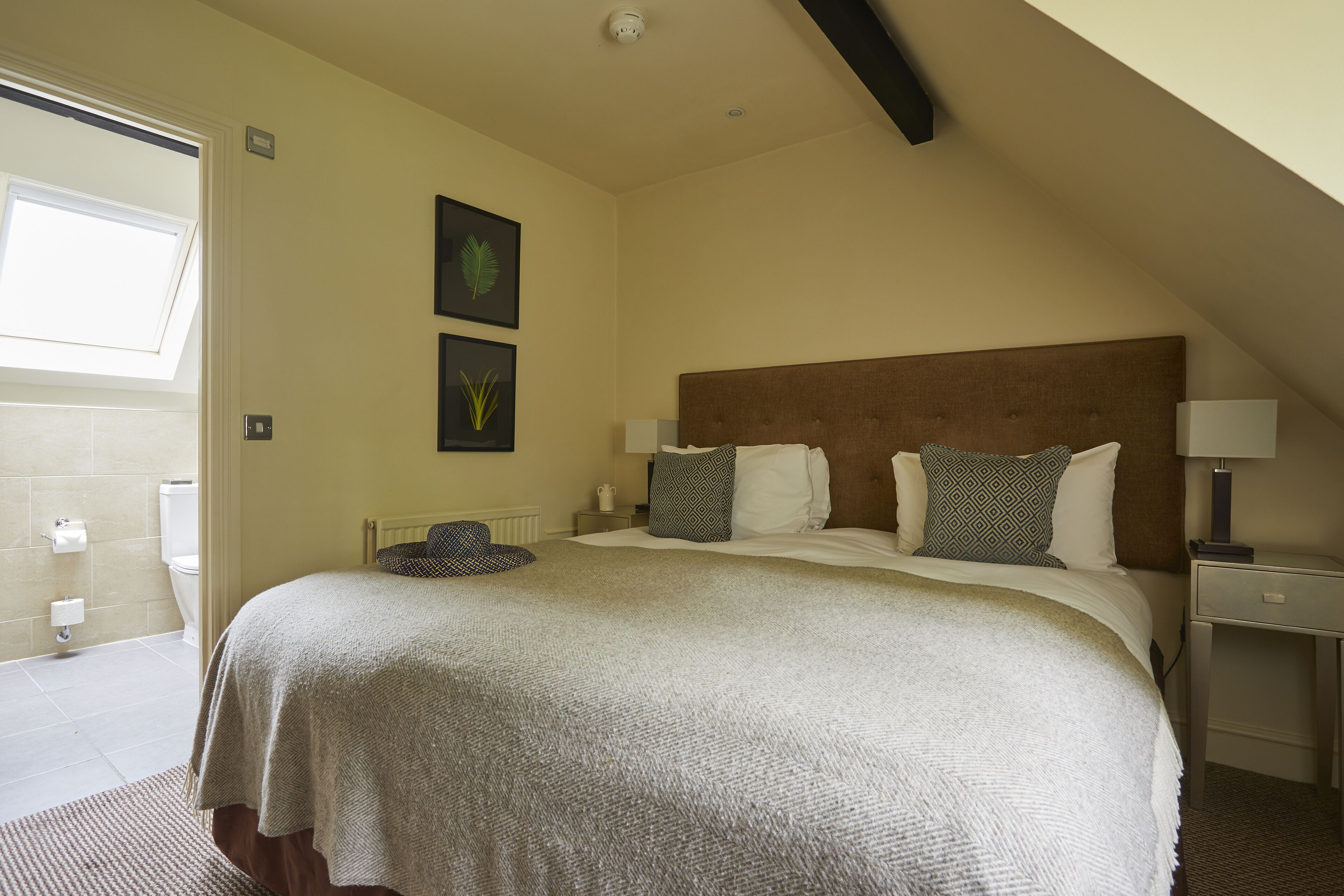 A bedroom with a large bed, a nightstand, a bedside table, and a window with a view of the outside.