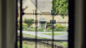 Une vue à travers la fenêtre d’un bâtiment en pierre, avec un canal en contrebas, un panneau indiquant la vitesse maximale autorisée et un arbre sur la droite.