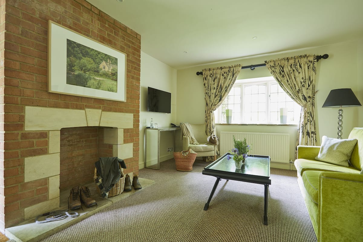 A living room with a fireplace, a television, a sofa, a coffee table, and a window with curtains.
