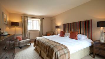 A bedroom with a large bed, a dresser, a nightstand, a lamp, a window with curtains, and a radiator.