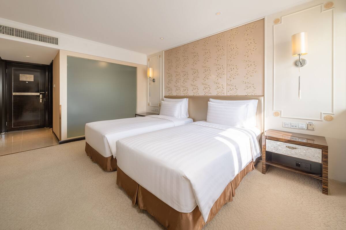 Une chambre d’hôtel avec deux lits, un grand miroir, une table de chevet et une porte.