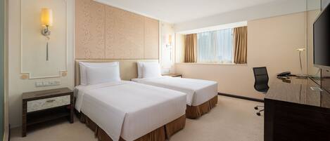 A hotel room with two beds, a desk, a chair, a TV, and a window with curtains.