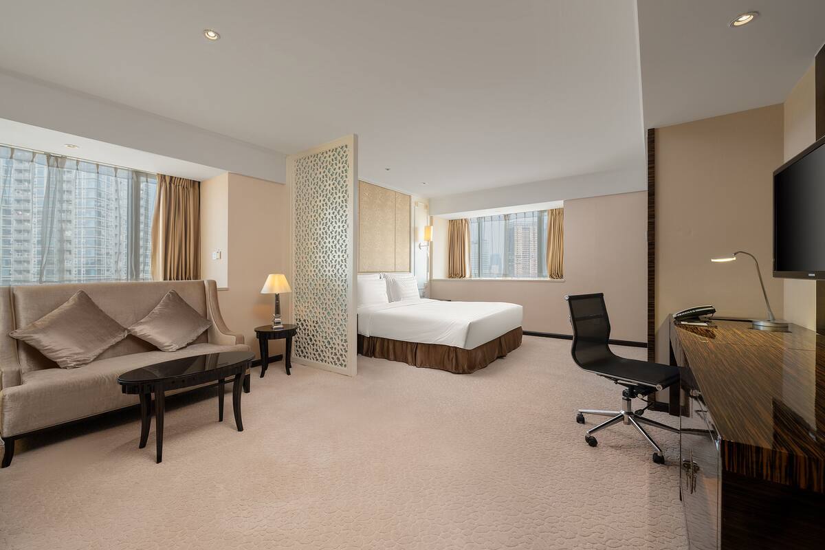 Une chambre d’hôtel équipée d’un lit, d’un canapé, d’un bureau, d’une chaise et d’une télévision.