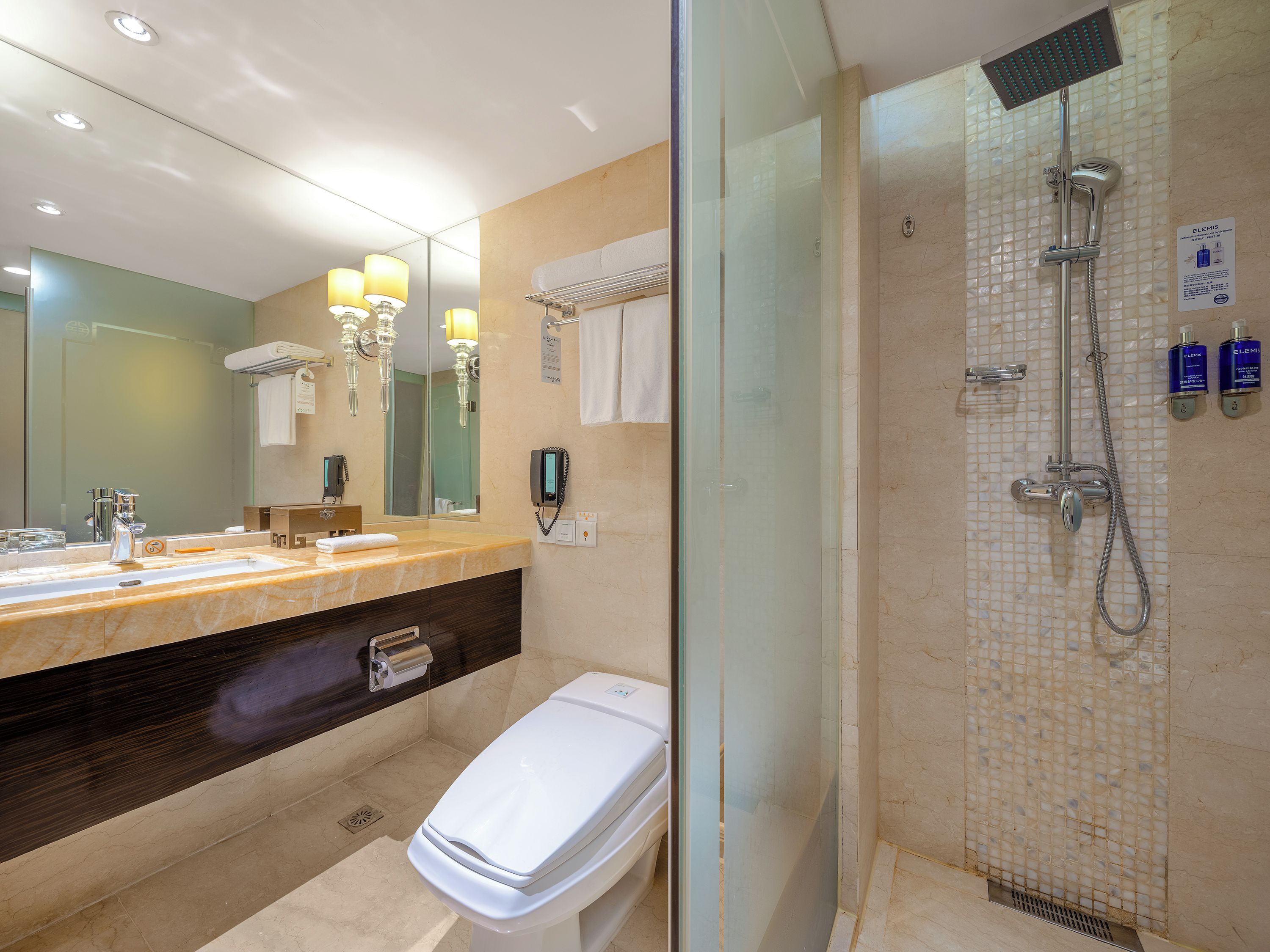 A modern bathroom with a glass-enclosed shower, a vanity with a mirror, and a toilet.
