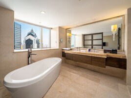 Un baño moderno con bañera, un espejo grande y una ventana con vistas a la ciudad.