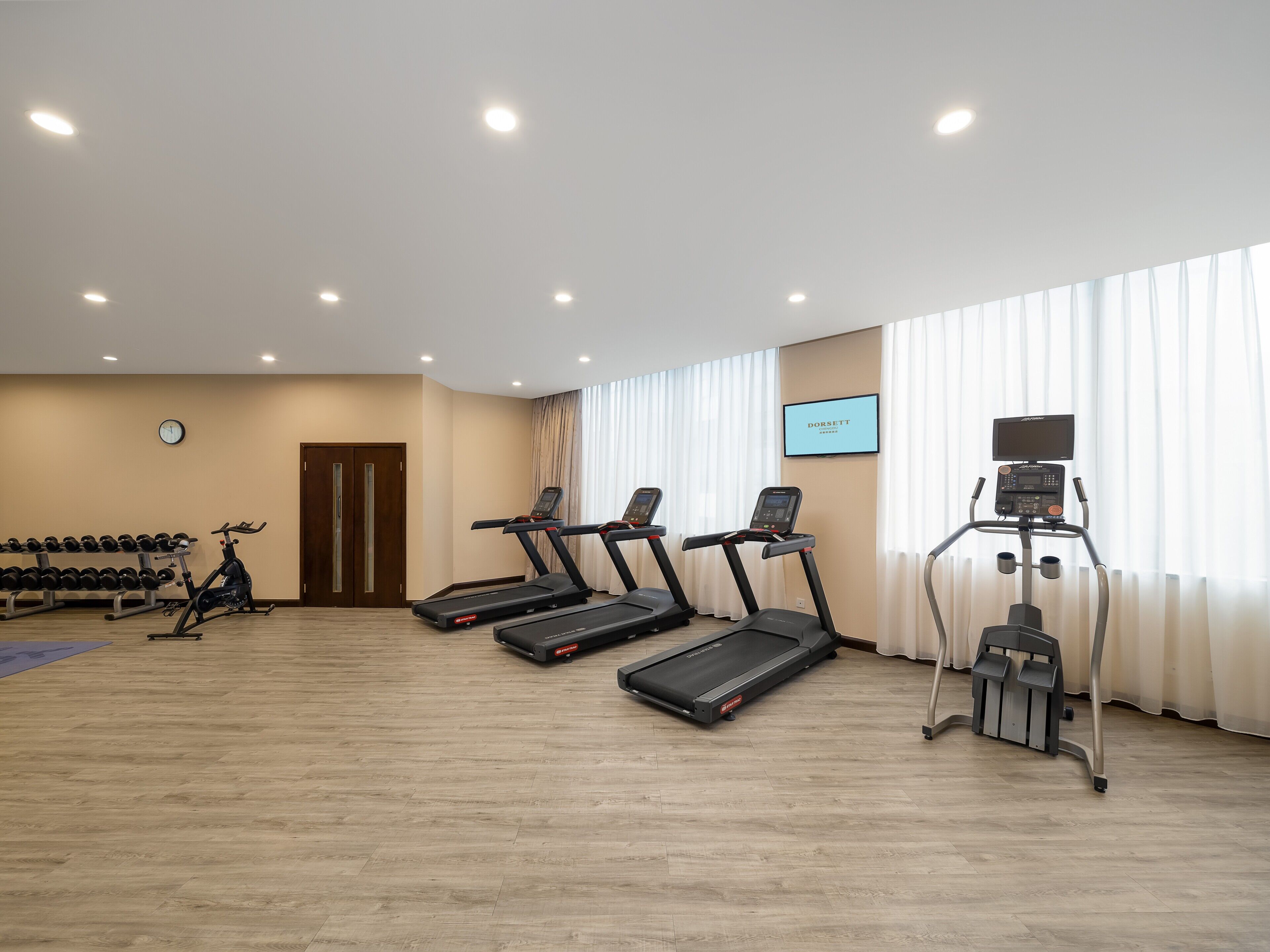 Une salle de sport équipée de tapis de course, d’un vélo d’appartement et d’haltères.