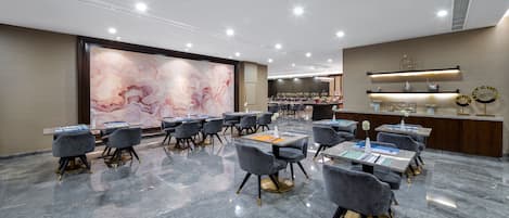 A modern conference room with marble flooring, grey upholstered chairs, and a large abstract painting on the wall.