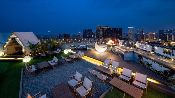 Una terraza en la azotea con mobiliario exterior y el horizonte de la ciudad al fondo.