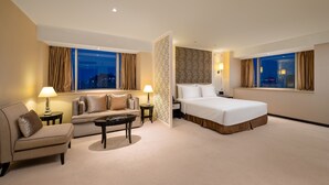 Una habitación de hotel con una cama, un sofá, una mesita de centro y una mesita de noche.