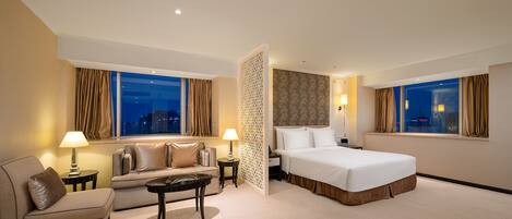 A hotel room with a bed, a sofa, a coffee table, and a nightstand.