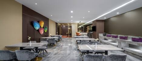 Un restaurante moderno con pisos de mármol, sillas grises tapizadas y una zona de bar con taburetes morados.