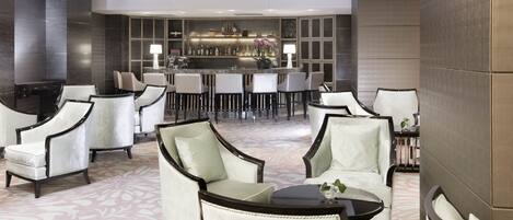 Een moderne hotel lobby met een bar, zitgedeelte en een kamerbreed tapijt met dessin.