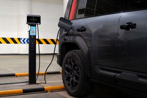 A vehicle charging at a station with a QR code and a digital display.