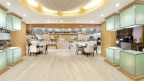 Un moderno vestíbulo de hotel con una zona de bar central, diferentes disposiciones de asientos y un techo decorativo.