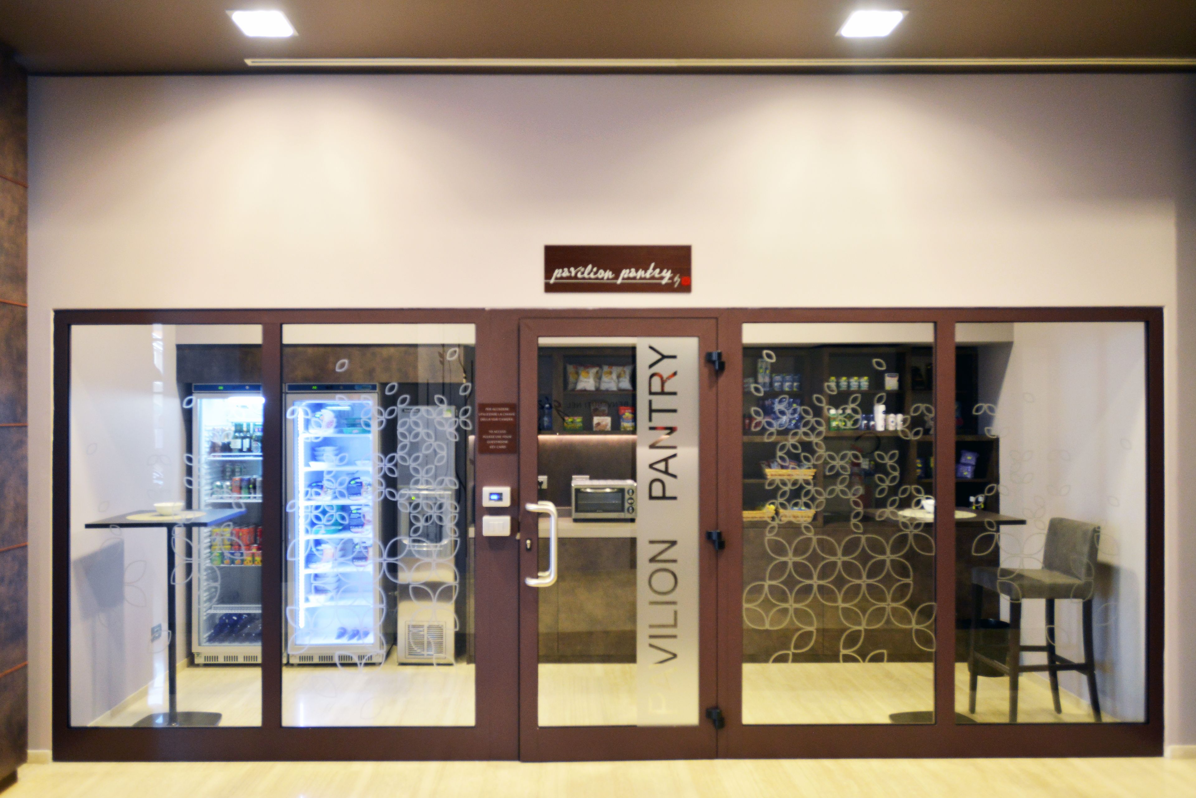 Una panadería con puerta de cristal, un letrero sobre la puerta y estantes llenos de productos horneados.