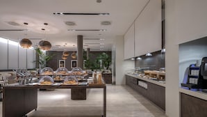 A modern kitchen area with a buffet setup, including a central island with food displays and a coffee station on the right.