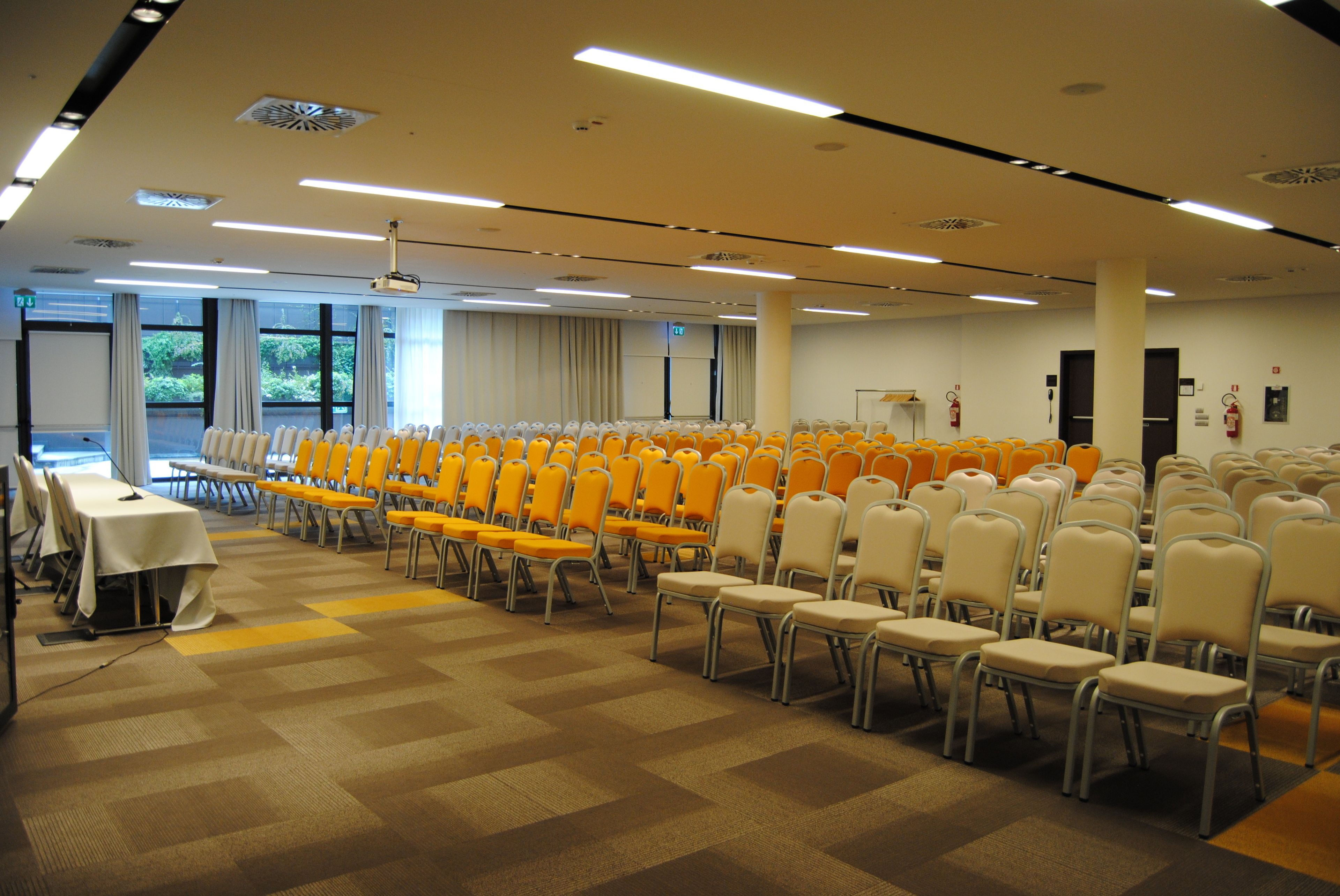 A conference room with rows of chairs, tables, and a projector screen.