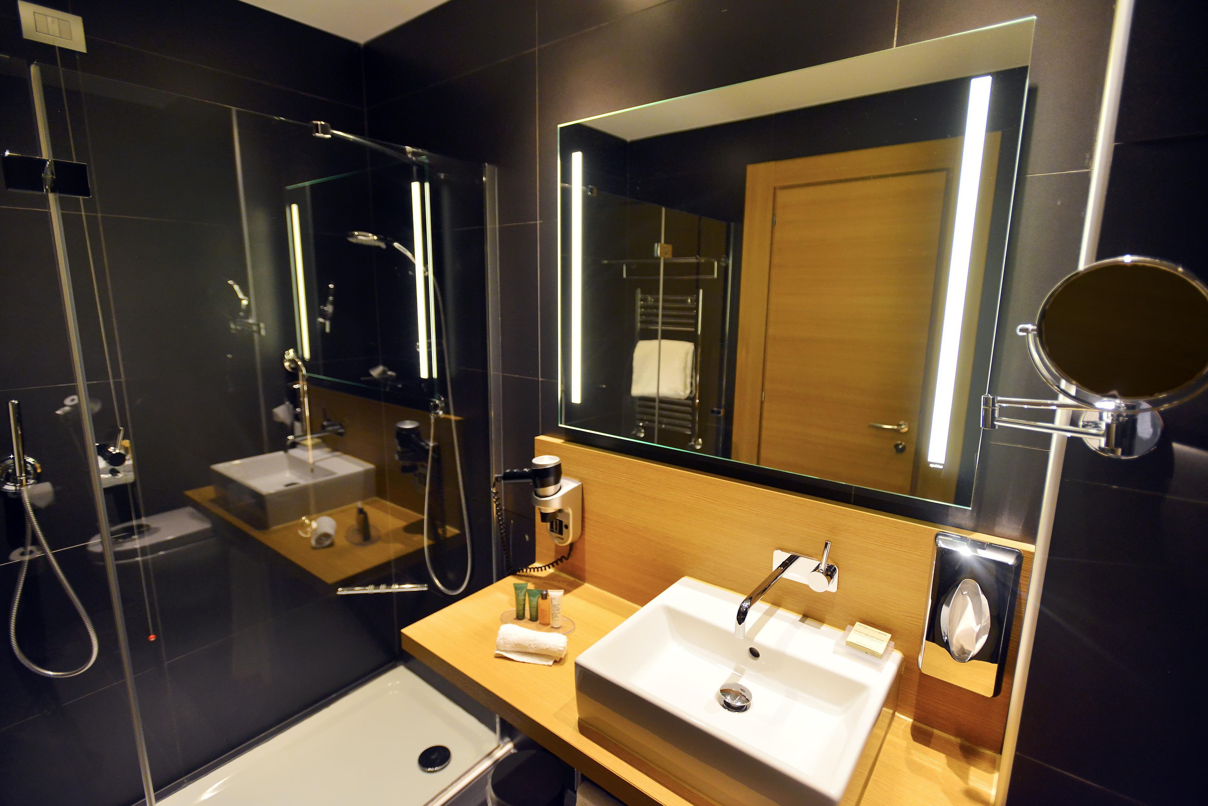 Un baño moderno con un espejo grande, dos lavamanos, una ducha y un inodoro.