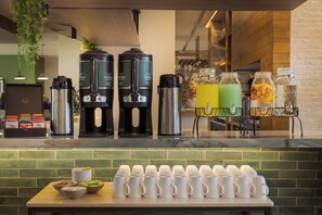 A coffee station with multiple coffee makers, a variety of mugs, and a selection of beverages.