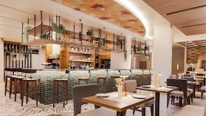 A modern bar area with a curved ceiling, bar stools, and a variety of plants.
