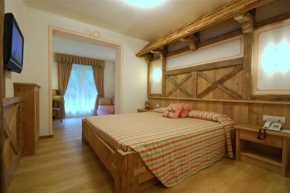 A wooden-framed bedroom with a bed, a nightstand, and a television.