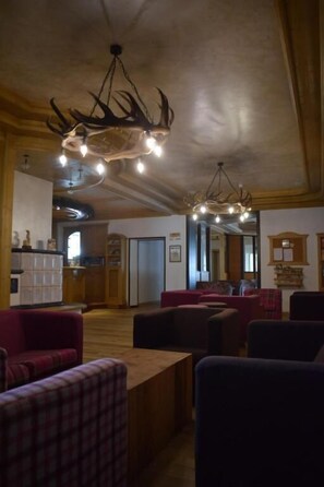 A spacious lobby with a large chandelier, comfortable seating, and a wooden ceiling.