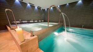 A spa area with a hot tub, a candle, and a tiled wall. - Bellaria (Predazzo)