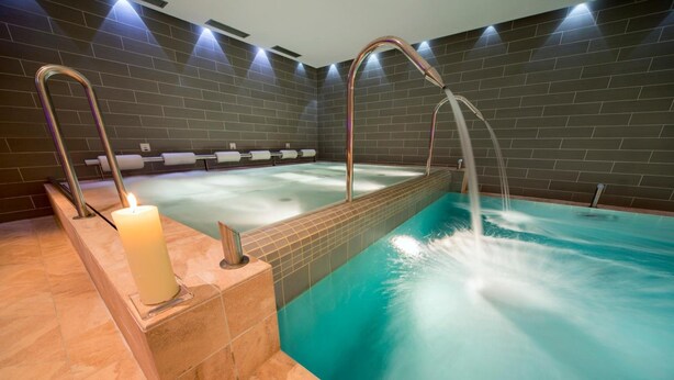 A spa area with a hot tub, a candle, and a tiled wall. - Bellaria (Predazzo)