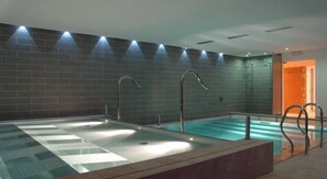 A modern indoor swimming pool with multiple lanes, clear water, and overhead lighting.