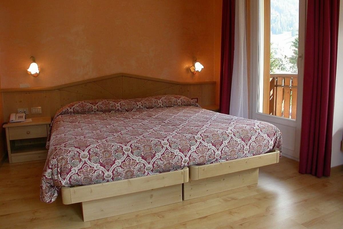 A bedroom with a wooden bed, two bedside tables, and a window with curtains.