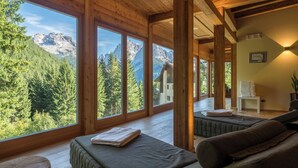 Une cabane en bois dotée de grandes fenêtres offrant une vue sur les montagnes.