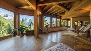 Un intérieur en bois, avec de grandes fenêtres, un plancher en bois et un coin salon équipé de serviettes.