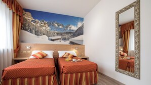 A hotel room with two beds, a large mirror, and a scenic wall mural. - Touring (Predazzo)