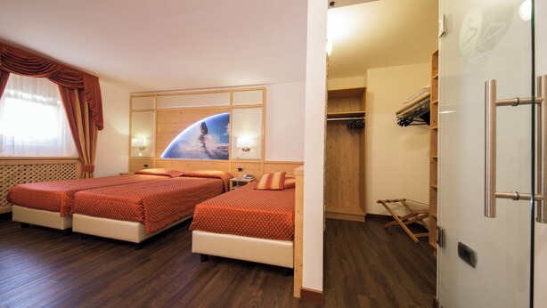 A hotel room with two beds, a wardrobe, and a mirror with a space-themed artwork. - Touring (Predazzo)