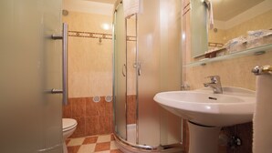A bathroom with a glass shower enclosure, a white sink, and a toilet. - Touring (Predazzo)