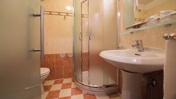 Un baño con cabina de ducha de vidrio, un lavamanos blanco y un inodoro.