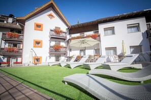 Un hotel con terraza en la azotea que incluye tumbonas y una zona de estar cubierta.