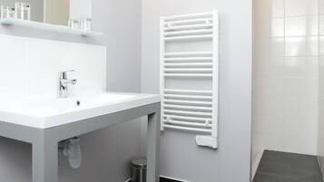 Une salle de bain moderne avec un lavabo blanc, un miroir et un porte-serviettes.