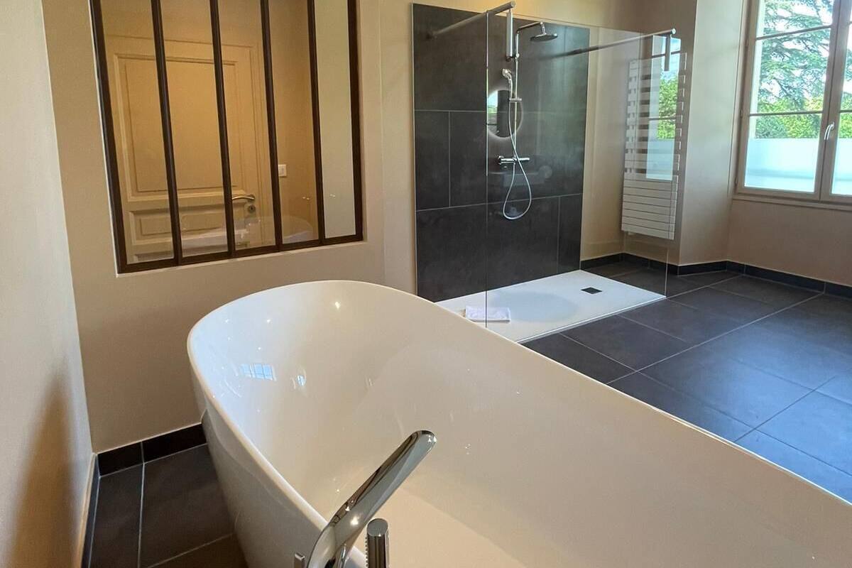 A modern bathroom with a freestanding bathtub, a glass-enclosed shower, and a large mirror.
