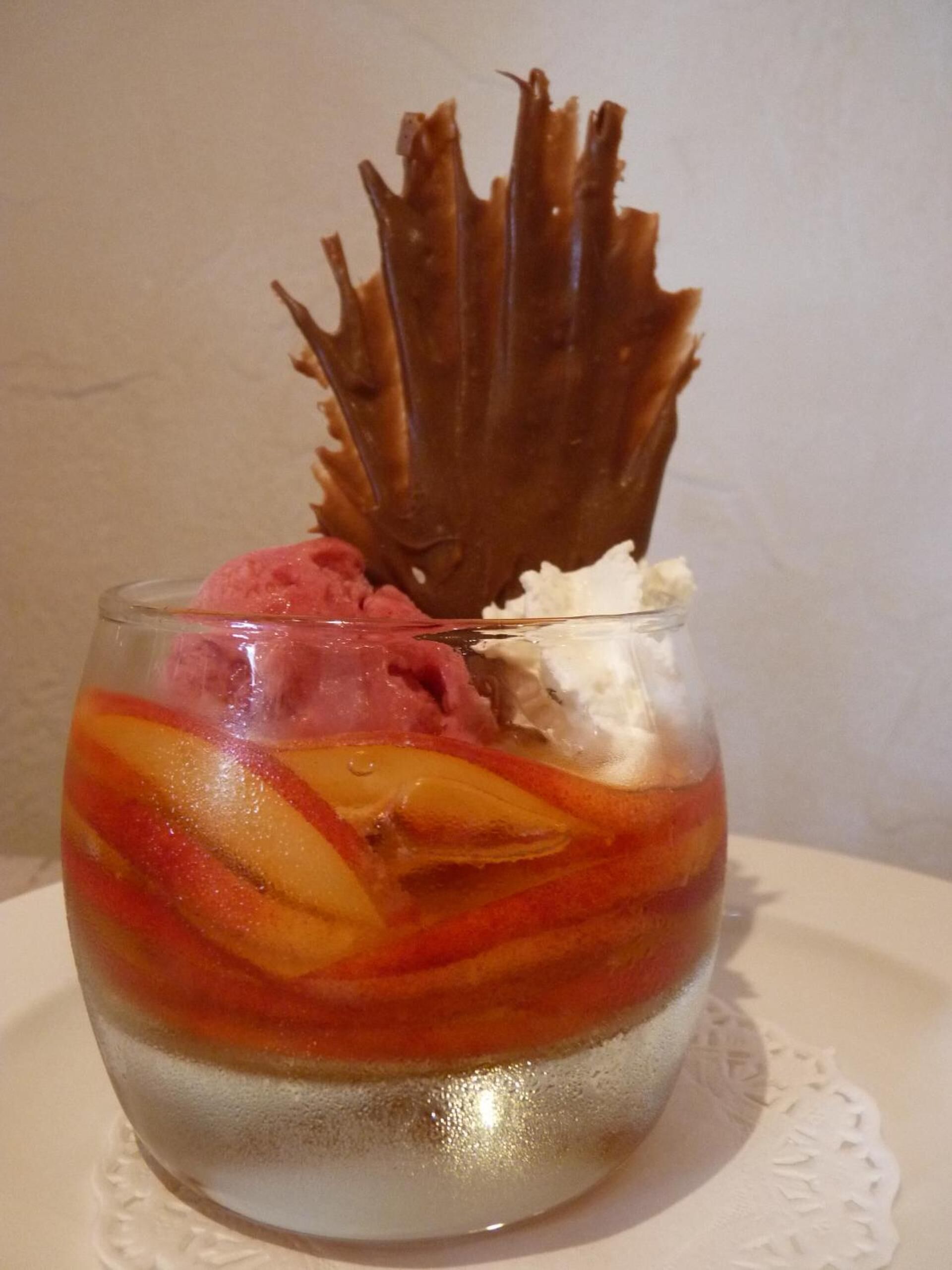 Un postre en un vaso transparente con varias capas, que incluyen fruta y crema batida.