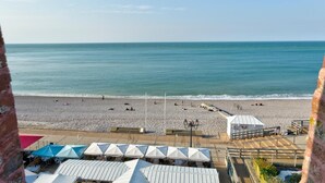 A beach with umbrellas and a building in the foreground. - Hotel Le Rayon Vert (Etretat)