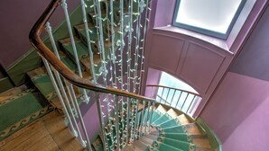 A spiral staircase with green patterned carpet, white balusters, and a wooden handrail. - Hotel Le Rayon Vert (Etretat)